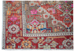 A handwoven vintage Persian rug featuring a geometric pattern in red, brown, and bright pink.