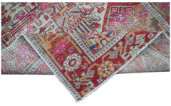 A vintage handwoven Persian rug featuring a geometric pattern in red, grey, and bright pink.