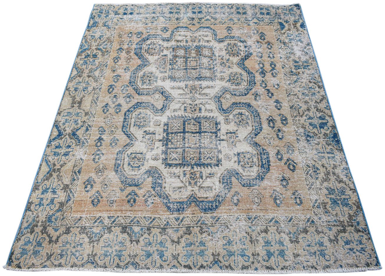 A vintage handwoven Persian rug featuring a distressed blue and tan geometric medallion pattern.