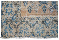 A vintage handwoven Persian rug featuring a distressed geometric pattern in blue, tan, and grey.