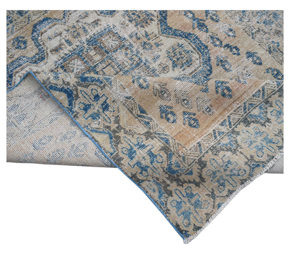 A handwoven vintage Persian rug featuring a faded blue and tan floral pattern on a wool pile.