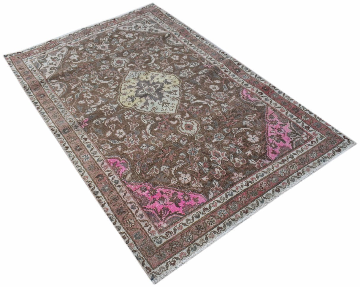 A vintage handwoven Persian rug featuring a brown field with floral patterns and pink accents.