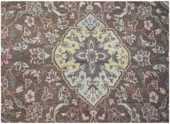 A vintage handwoven Persian rug featuring a central yellow medallion on a brown floral field.