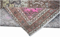 A vintage handwoven Persian rug with a distressed floral pattern in shades of pink and brown.