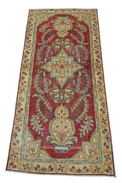 A vintage handmade Persian runner rug featuring a floral medallion pattern on a red field.