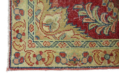 A corner view of a vintage Persian rug featuring intricate floral patterns in red, green, and tan.