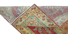 A corner of a vintage Persian rug folded over to show its intricate red, blue, and cream pattern.