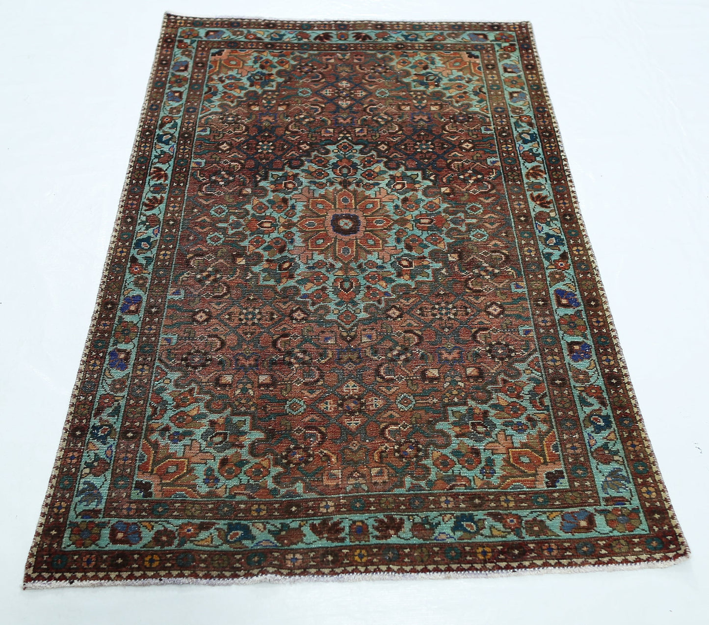 A rectangular vintage Persian rug featuring a central floral medallion in shades of red and teal.