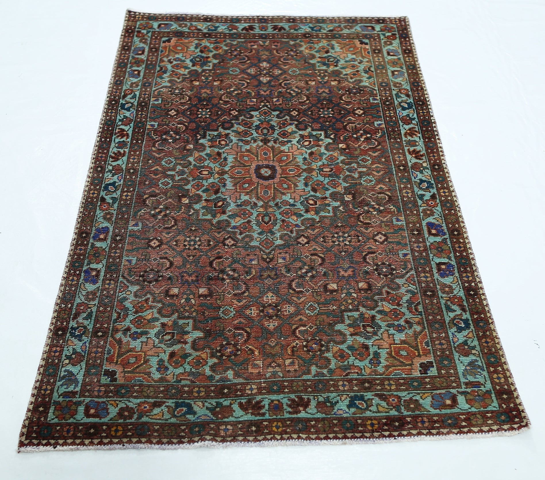 A rectangular vintage Persian rug featuring a central floral medallion in shades of red and teal.