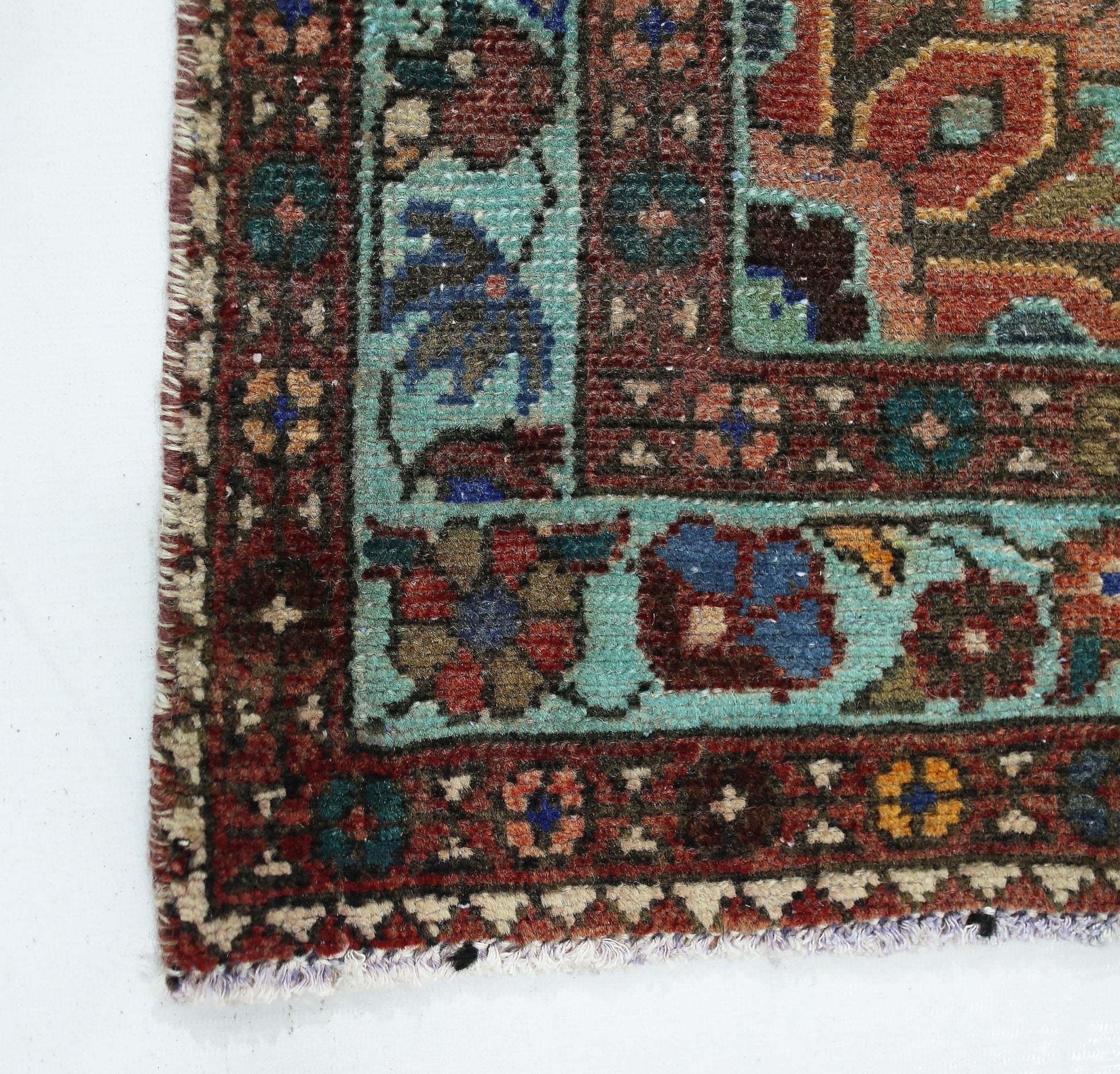 A corner view of a vintage handmade Persian rug featuring intricate floral patterns in wool.