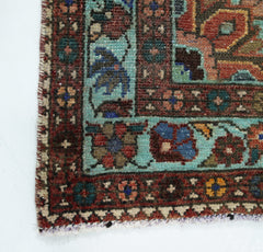A corner view of a vintage handmade Persian rug featuring intricate floral patterns in wool.