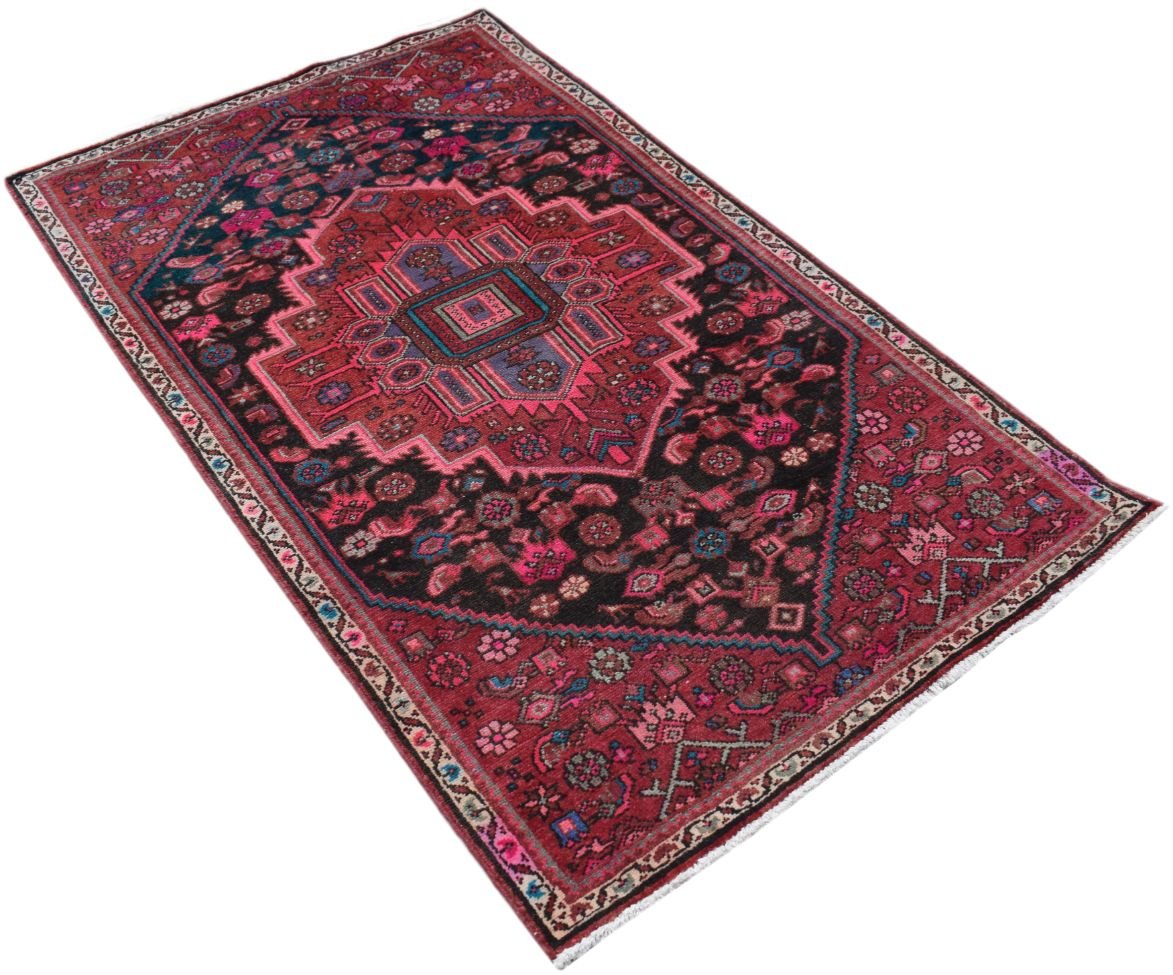 A rectangular handmade Persian rug featuring a traditional geometric pattern in red and black.