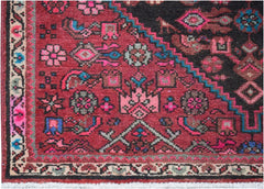 A vintage Persian wool rug featuring a geometric tribal pattern in red, black, and pink tones.