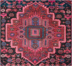 A vintage handmade Persian wool rug featuring a geometric medallion in shades of red and purple.