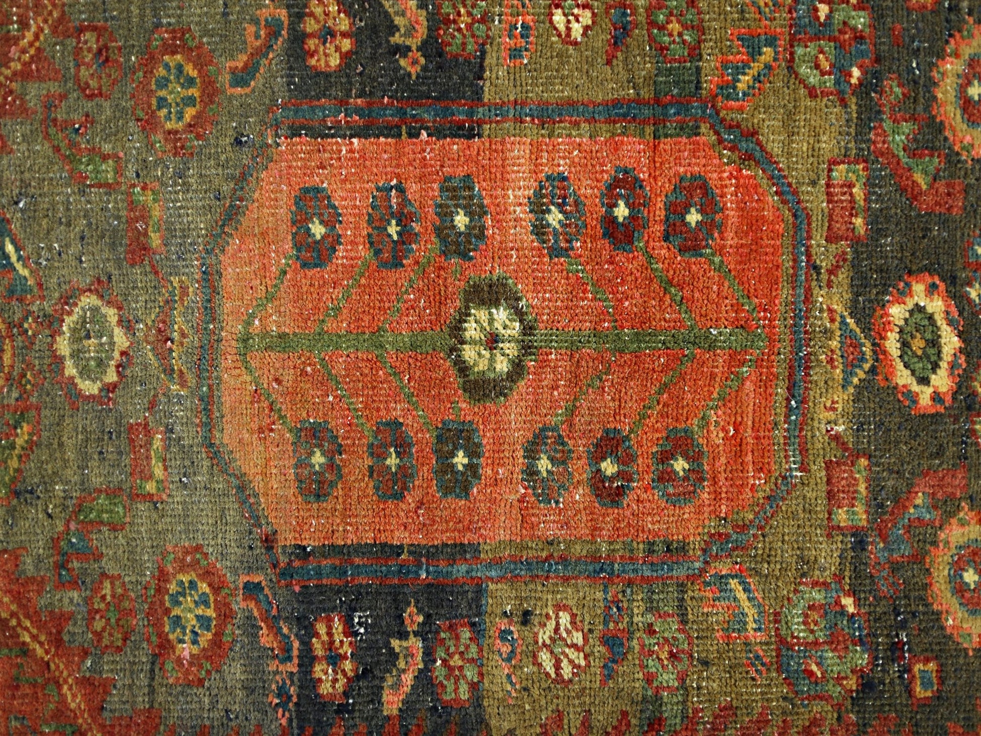 A vintage handmade Persian rug featuring a central orange medallion with floral motifs.