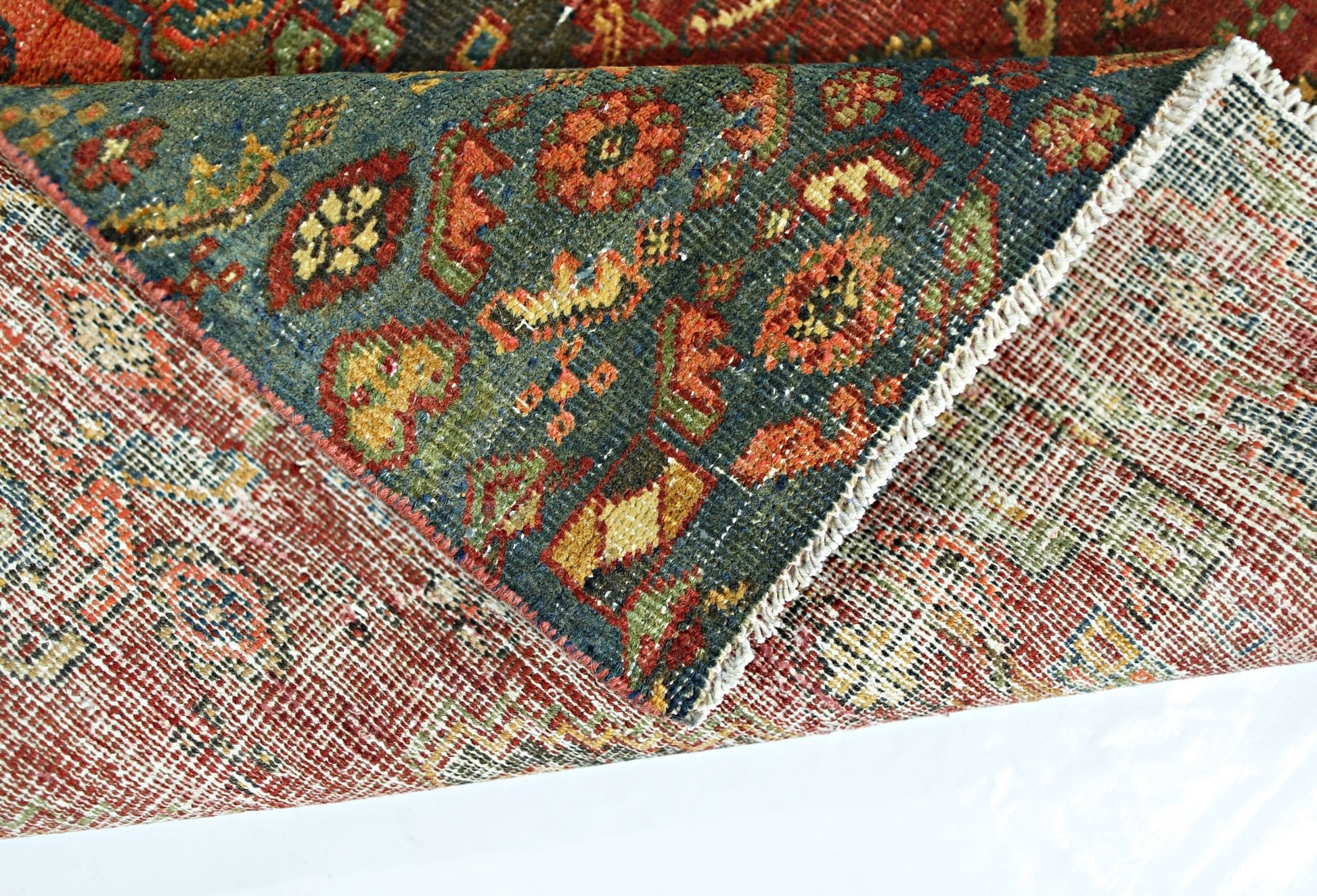 A folded vintage Persian rug featuring a dark blue field with intricate floral patterns in wool.