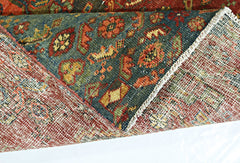 A folded vintage Persian rug featuring a dark blue field with intricate floral patterns in wool.