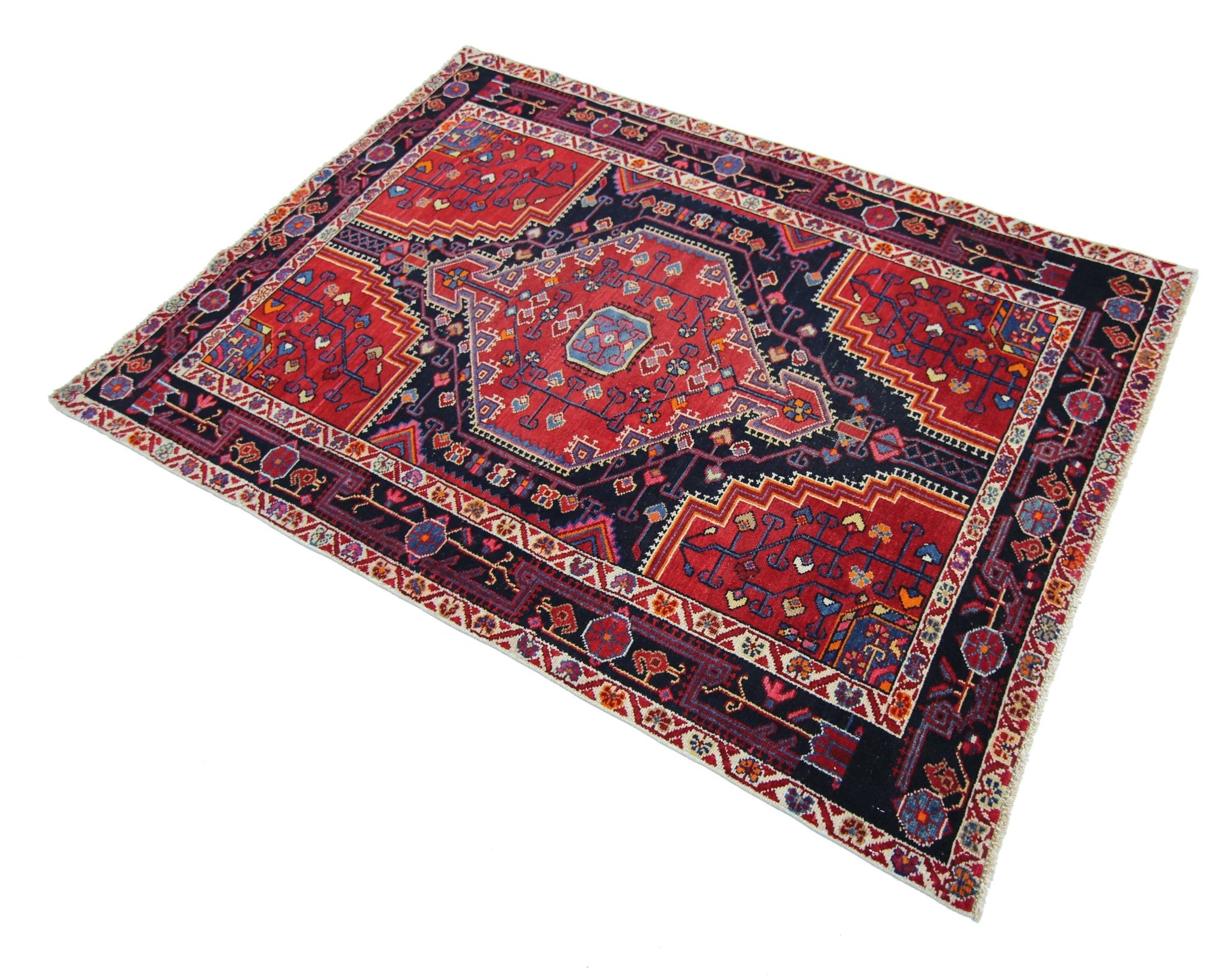 A handmade vintage Persian rug featuring a geometric red medallion on a dark blue field.