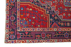 A vintage handmade Persian rug featuring intricate geometric patterns in red, blue, and cream.