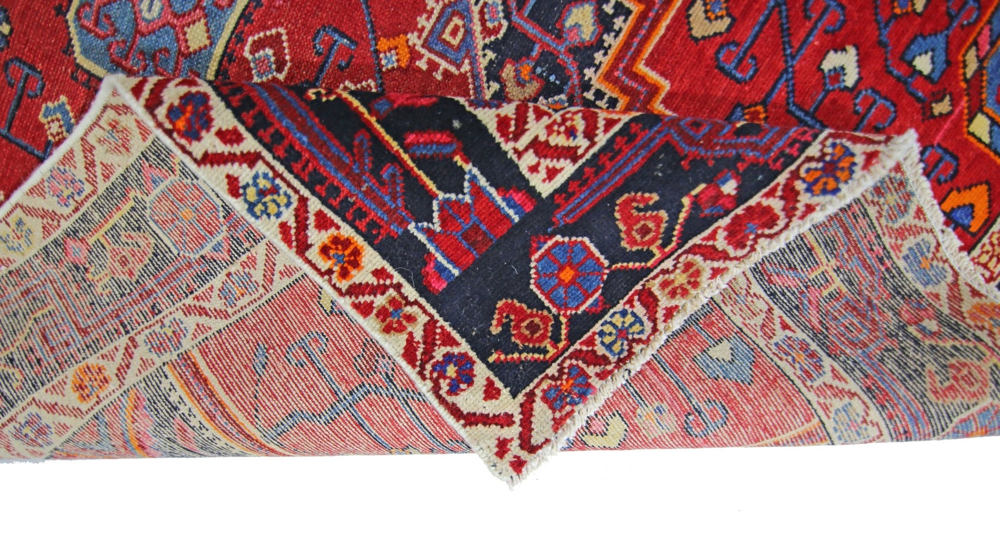 A vintage handmade Persian rug with a red field and intricate geometric patterns.
