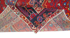 A vintage handmade Persian rug with a red field and intricate geometric patterns.