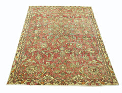 A vintage handmade Persian rug featuring a floral pattern in shades of red, green, and beige.