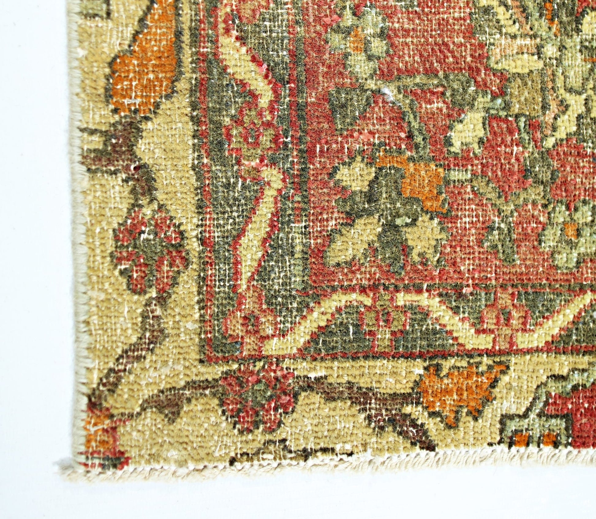 A close-up of a vintage handmade Persian rug featuring intricate floral patterns in red and green.