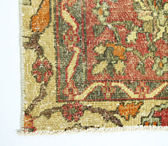 A close-up of a vintage handmade Persian rug featuring intricate floral patterns in red and green.