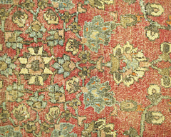 A vintage handmade Persian rug featuring a floral pattern in shades of red, green, and cream.