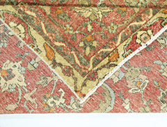 A folded corner of a vintage Persian rug featuring a red field with intricate floral patterns.