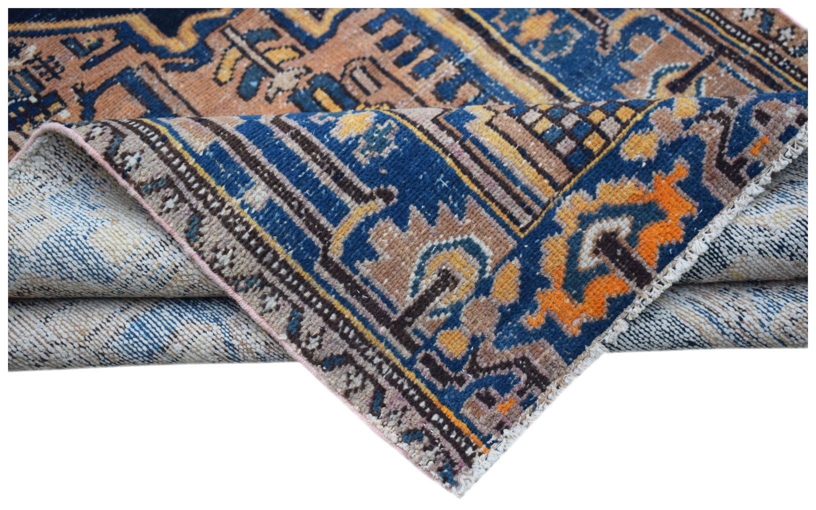 A folded vintage Persian rug featuring intricate geometric patterns in blue, orange, and tan.