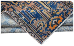 A folded vintage Persian rug featuring intricate geometric patterns in blue, orange, and tan.
