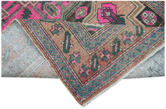 A vintage handwoven Persian rug featuring geometric patterns in vibrant pink, blue, and tan tones.