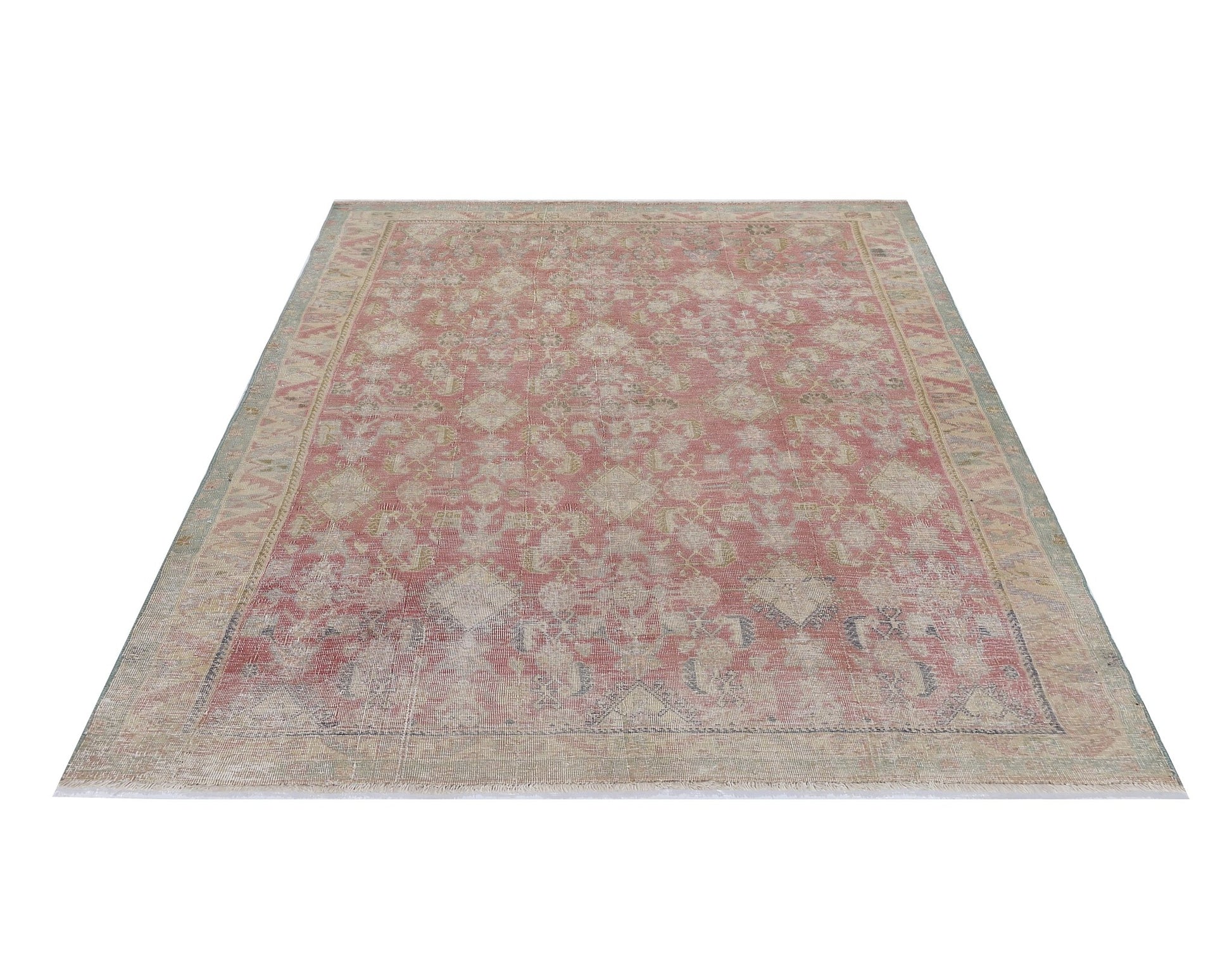 A vintage handmade Persian rug featuring a faded pink and beige geometric pattern.