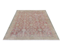 A vintage handmade Persian rug featuring a faded pink and beige geometric pattern.