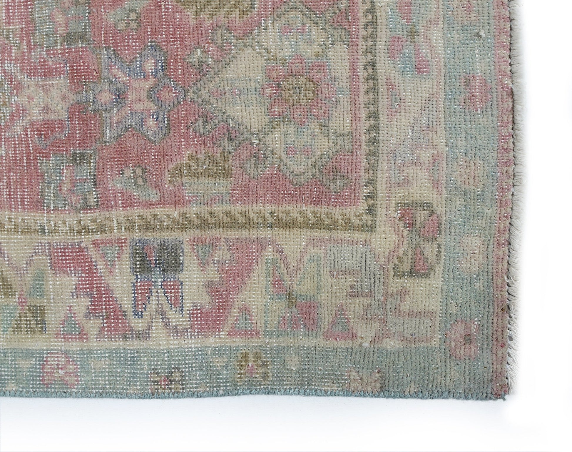 A vintage Persian rug featuring a faded floral pattern in shades of pink, blue, and beige.