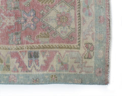 A vintage Persian rug featuring a faded floral pattern in shades of pink, blue, and beige.