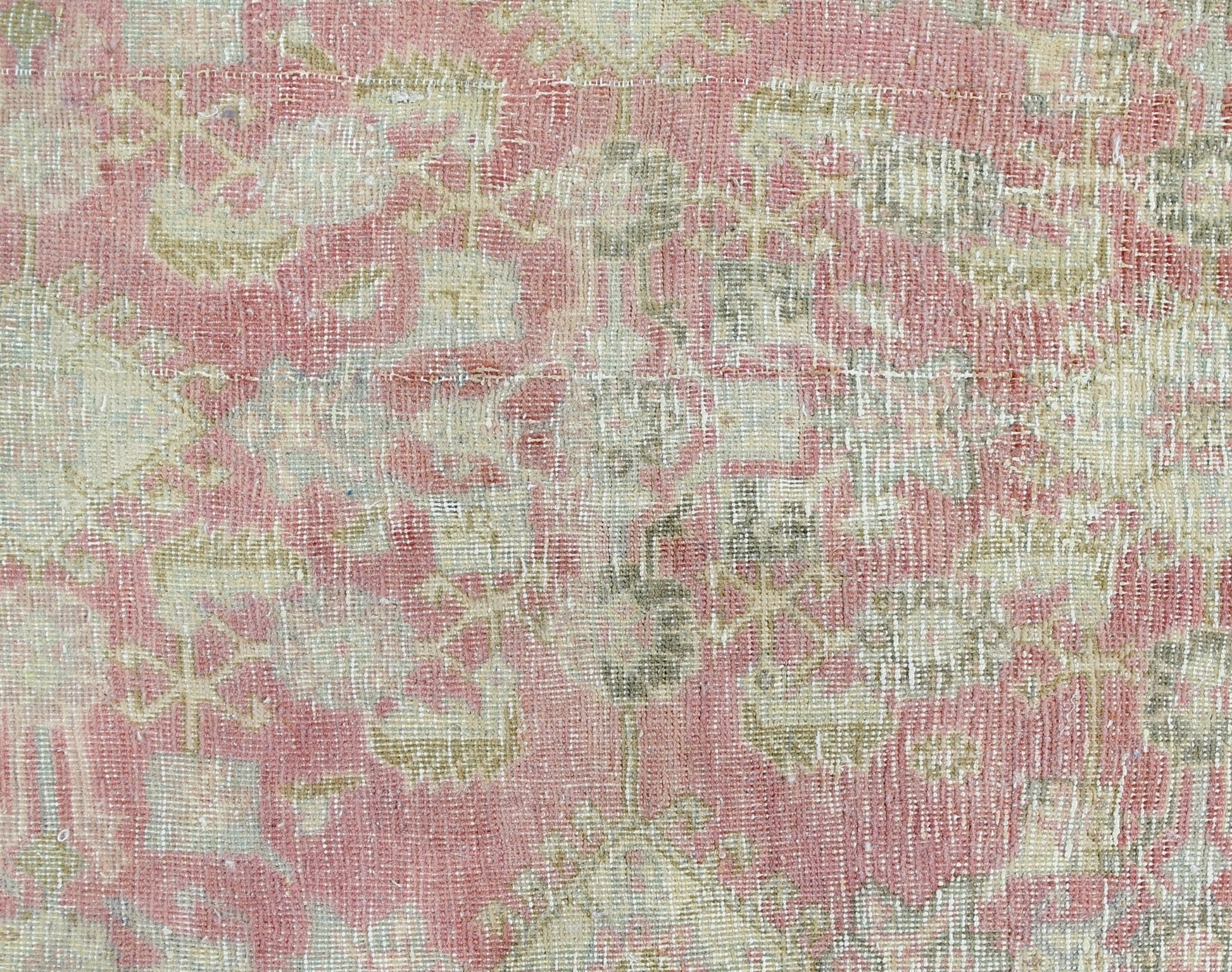A vintage Persian rug featuring a faded floral pattern in shades of pink and beige.