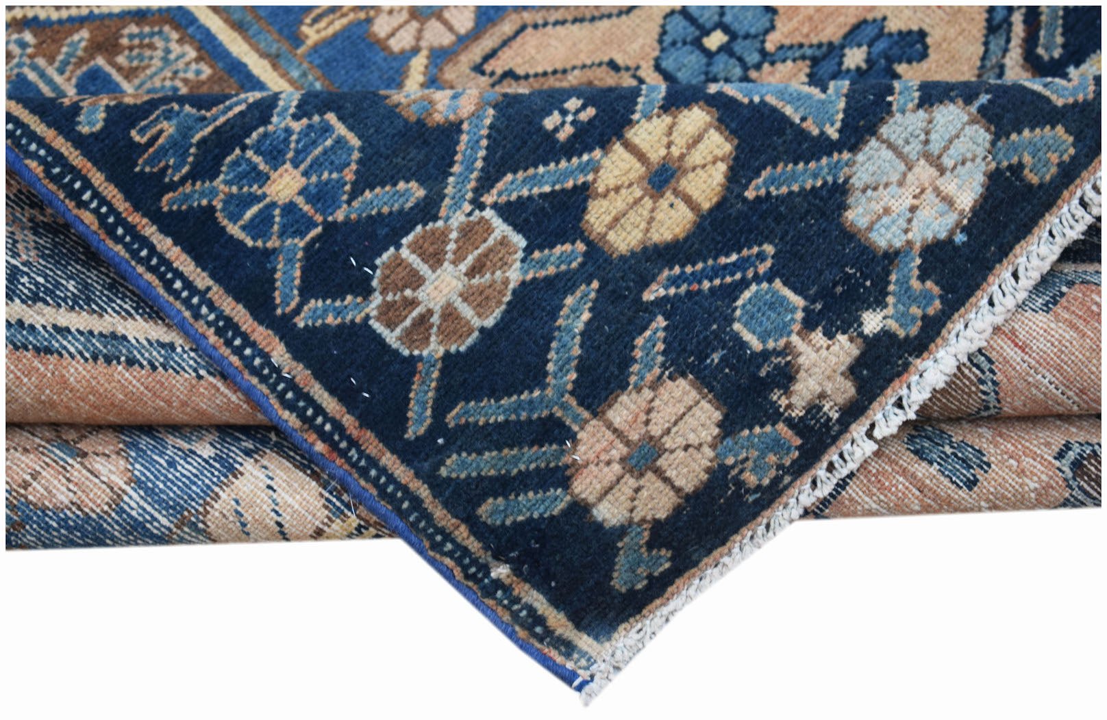 A handwoven vintage Persian rug featuring a dark blue field with floral patterns and beige accents.