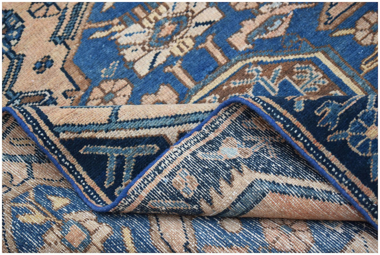 A handwoven vintage Persian rug featuring intricate floral patterns in blue and beige tones.