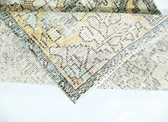 A folded vintage Persian rug featuring a faded geometric pattern in muted tones.