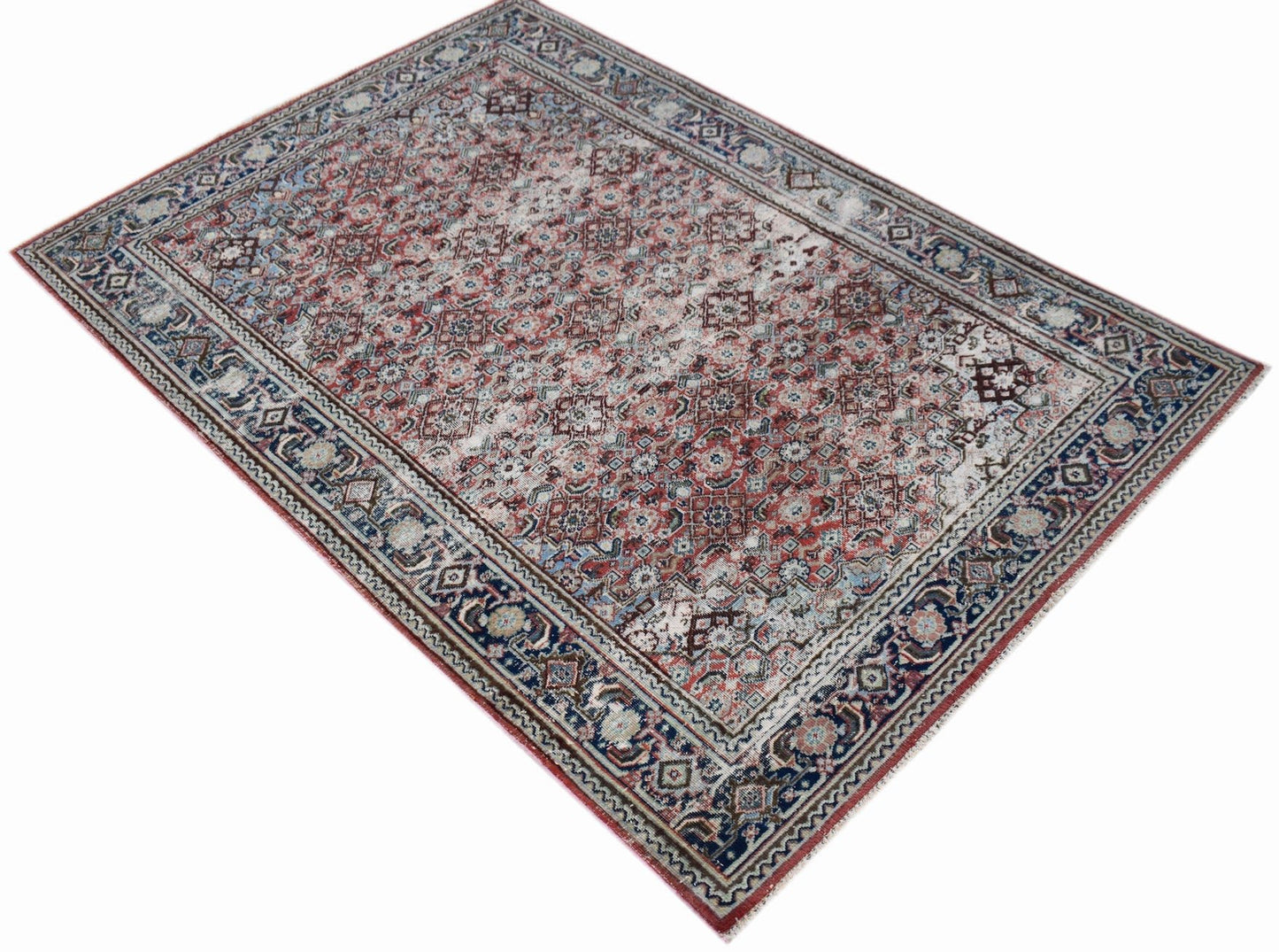 A rectangular vintage Persian rug featuring a faded red and blue geometric pattern.