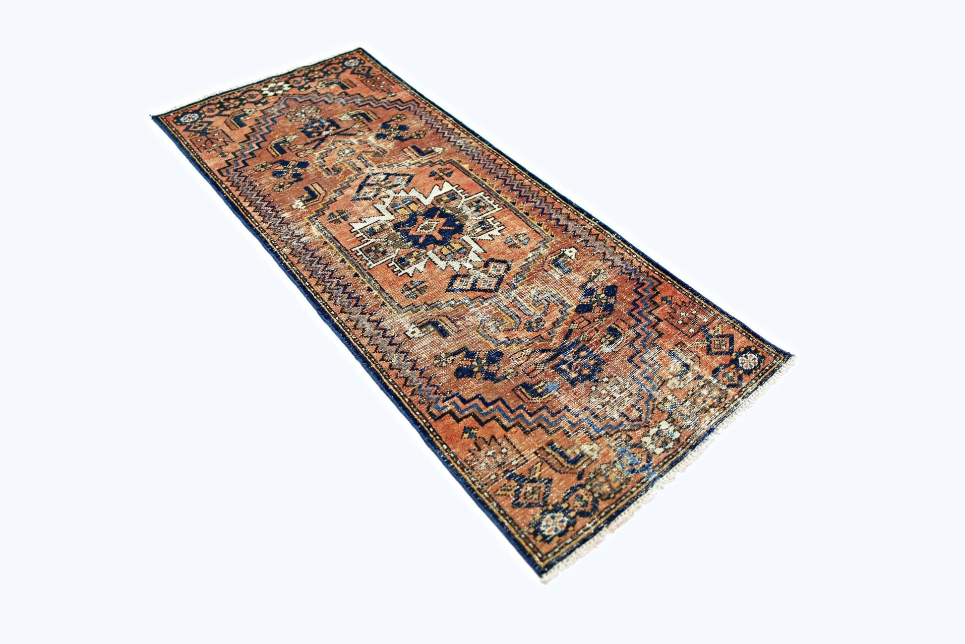 A vintage handmade Persian runner rug featuring geometric patterns in rust, blue, and cream tones.