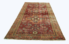 A rectangular vintage Persian rug with a red field and intricate geometric patterns.