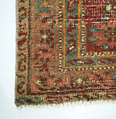 A close-up of a handmade vintage Persian rug featuring intricate geometric patterns in red and green.