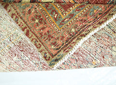 A folded vintage Persian rug featuring intricate geometric patterns in red, blue, and gold tones.