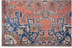 A handwoven vintage Persian rug featuring intricate floral patterns in blue and coral tones.