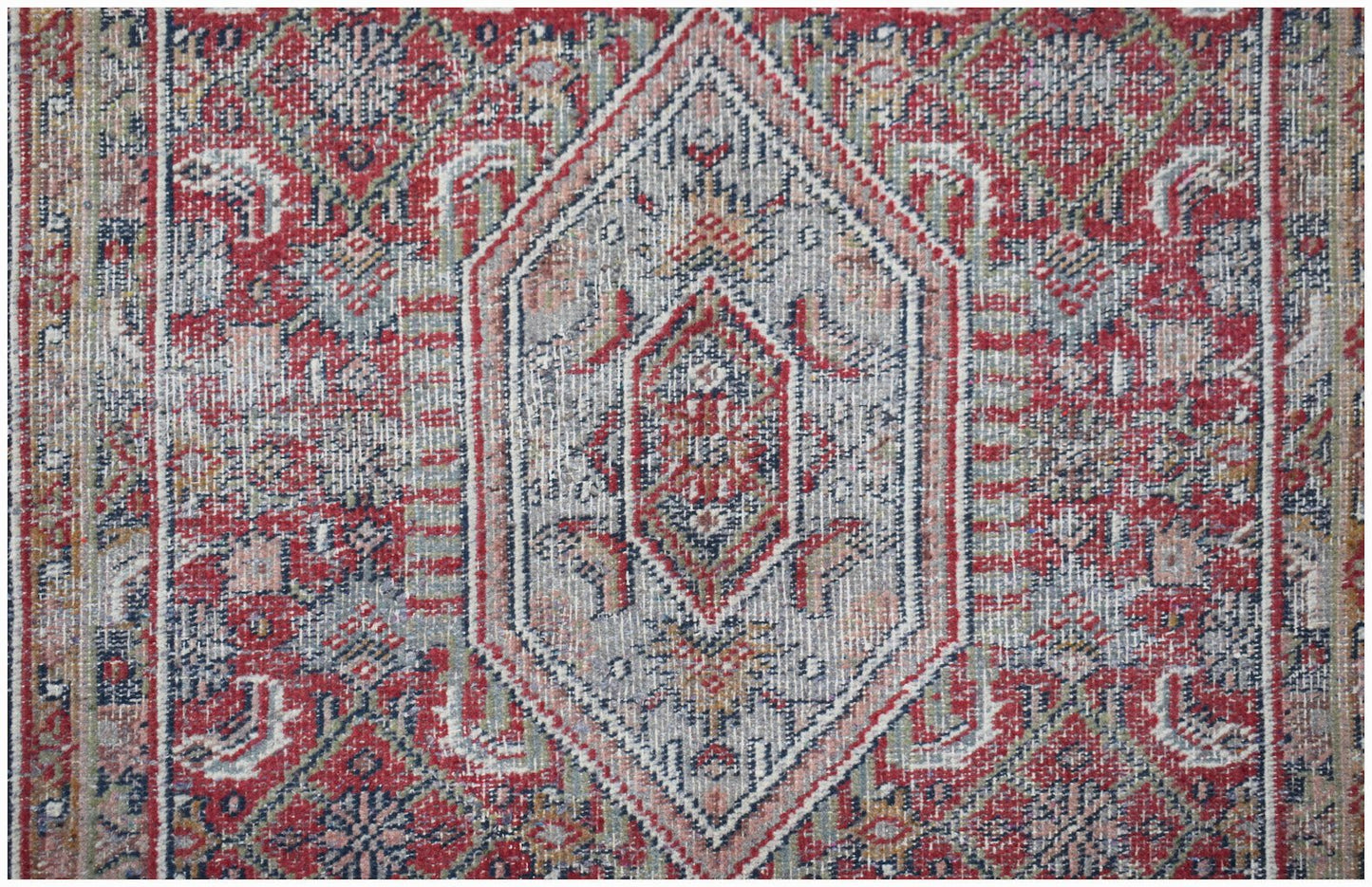 A vintage handwoven Persian rug featuring a central diamond medallion in red, blue, and cream.