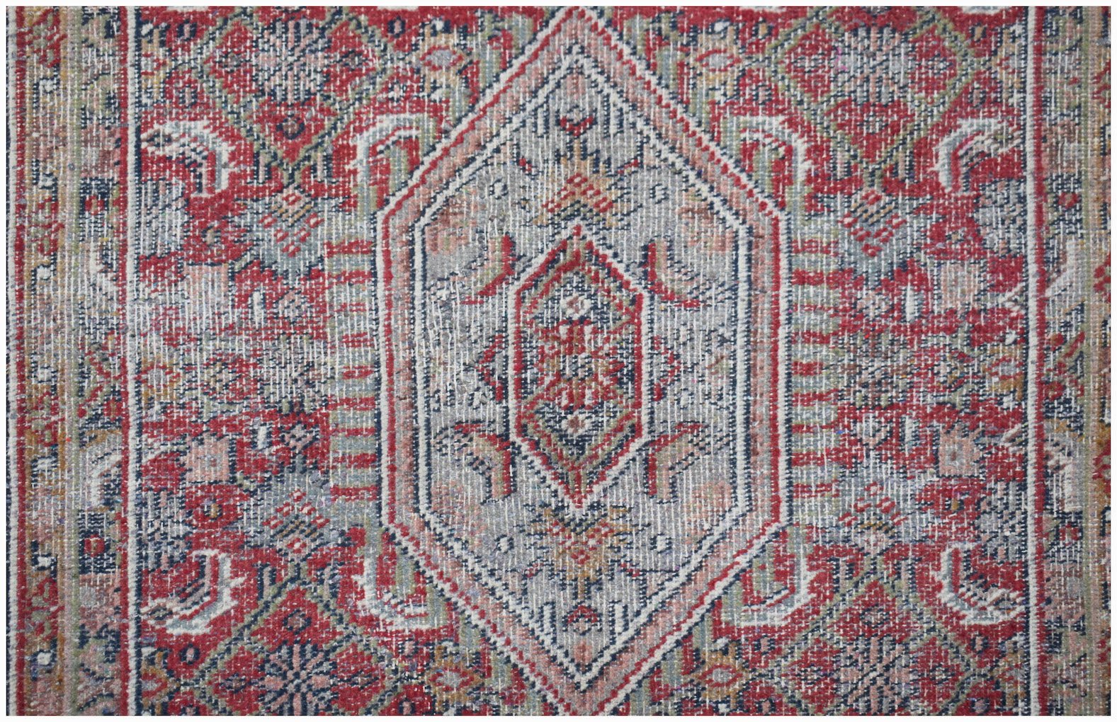 A vintage handwoven Persian rug featuring a central diamond medallion in red, blue, and cream.