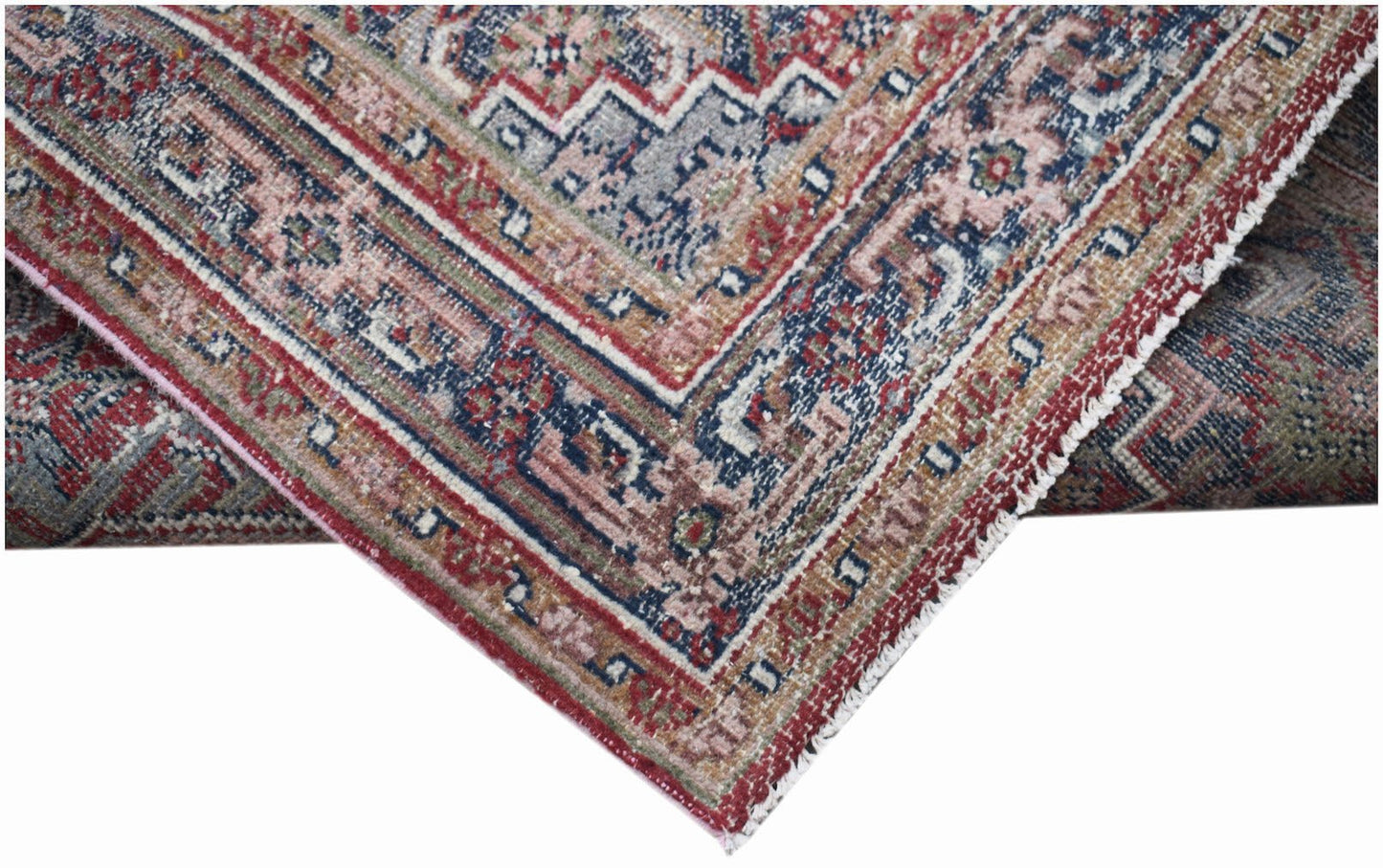 A handwoven vintage Persian rug featuring intricate geometric patterns in faded red and blue tones.